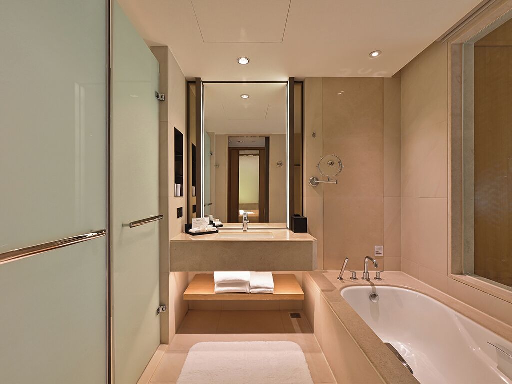 Un baño moderno con cabina de ducha de vidrio, una bañera independiente y un lavabo con espejo.