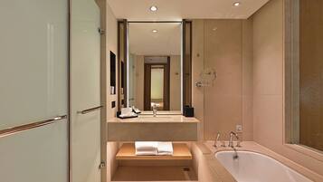 A modern bathroom with a glass shower enclosure, a freestanding bathtub, and a vanity with a mirror.