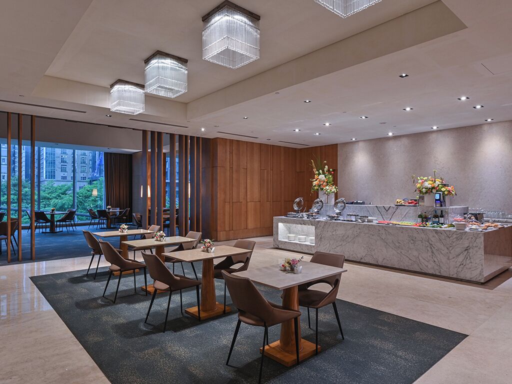 Un hall d’hôtel moderne avec un comptoir d’accueil, un espace salon et de grandes fenêtres.