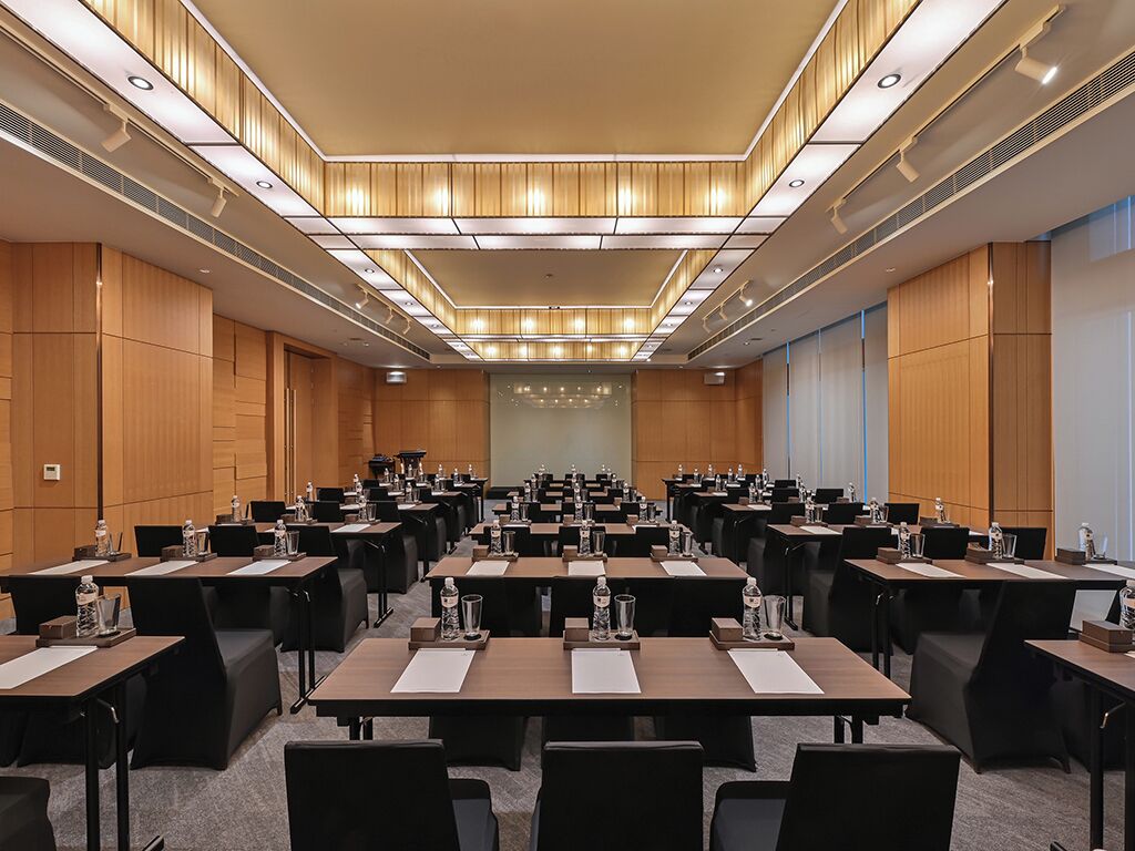 A conference room with multiple tables and chairs, equipped with water bottles and nameplates.