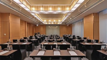 A conference room with multiple tables and chairs, equipped with water bottles and nameplates.