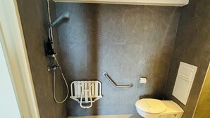 A small, modern bathroom with a toilet, a shower, and a handrail. - ibis Douai Dechy (Dechy)