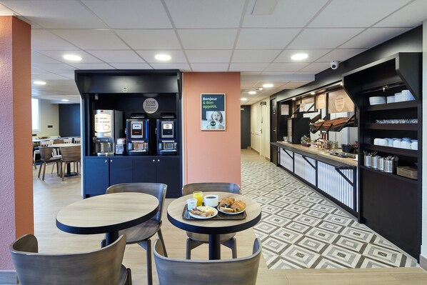 A breakfast area with tables, chairs, and a coffee machine. - B&B HOTEL Paris Nord Gonesse Parc des Expos (Gonesse)