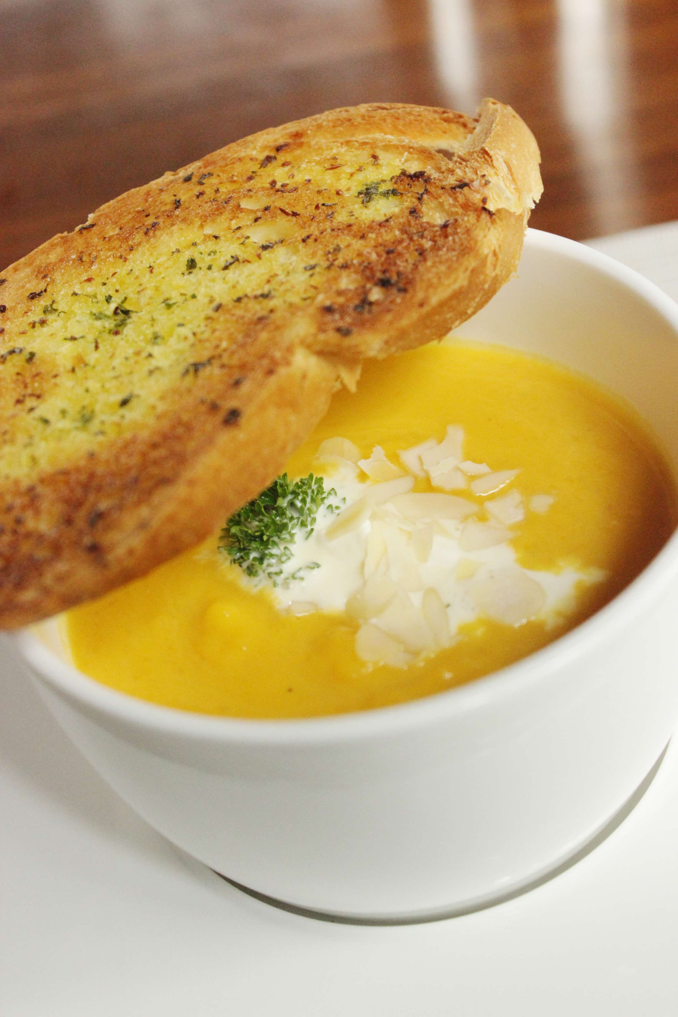 Un tazón de sopa con una rebanada de pan tostado encima.