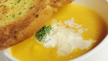 Un tazón de sopa con una rebanada de pan tostado encima.