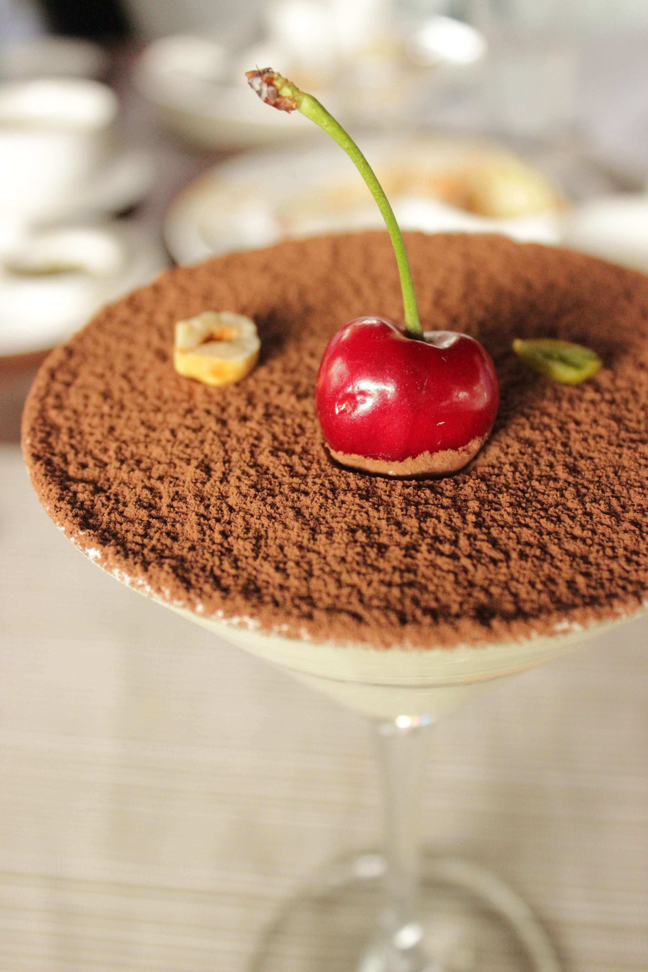 A dessert with a cherry on top, dusted with cocoa powder.