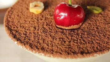 A dessert with a cherry on top, dusted with cocoa powder.