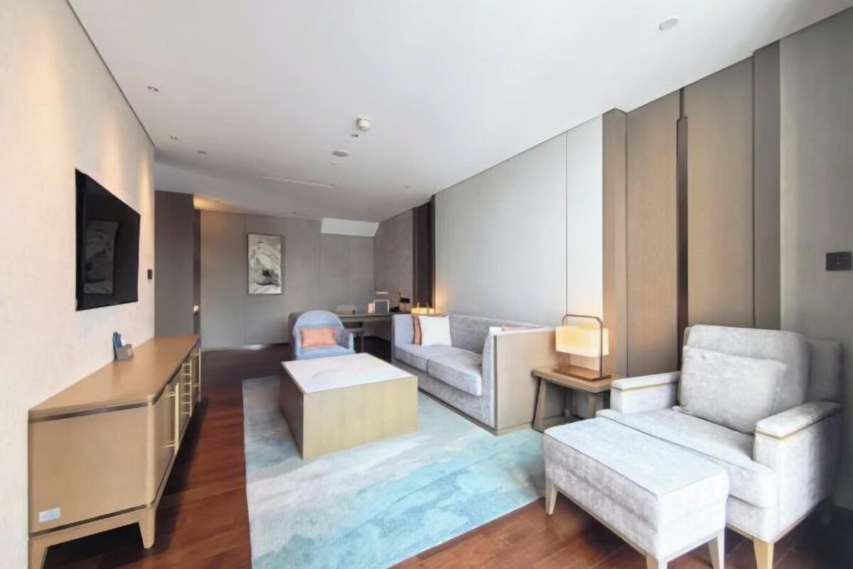 Een moderne woonkamer met een bank, fauteuil, salontafel en een bijzettafeltje met een lamp.