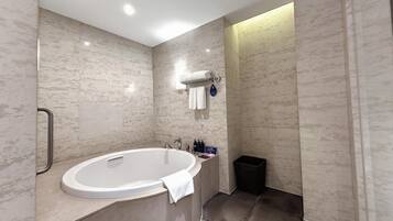 A modern bathroom with a freestanding bathtub, a towel rack, and a trash bin.