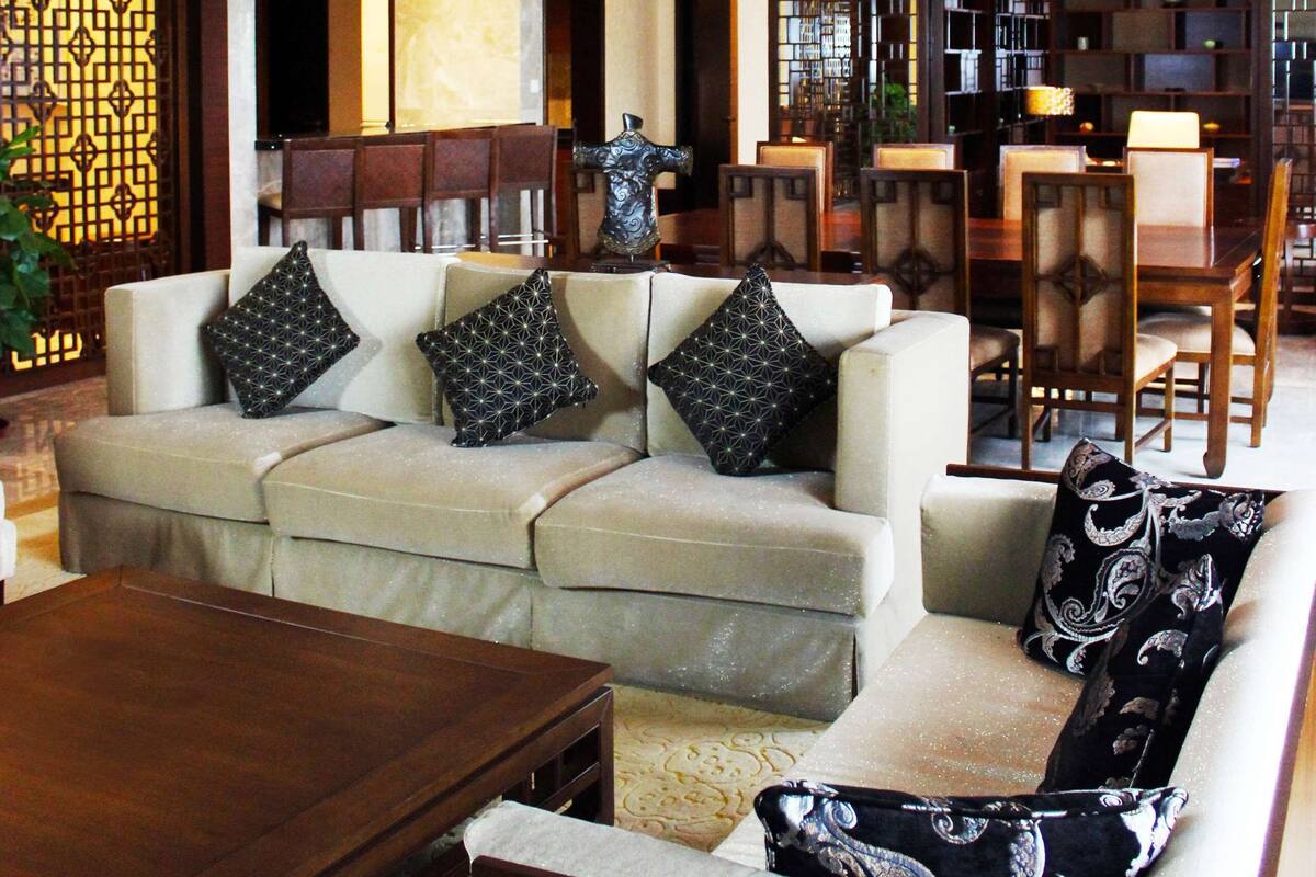 Amplia sala de estar con techo alto, un conjunto de sofás, una mesa de centro de madera y un comedor con sillas y una mesa.