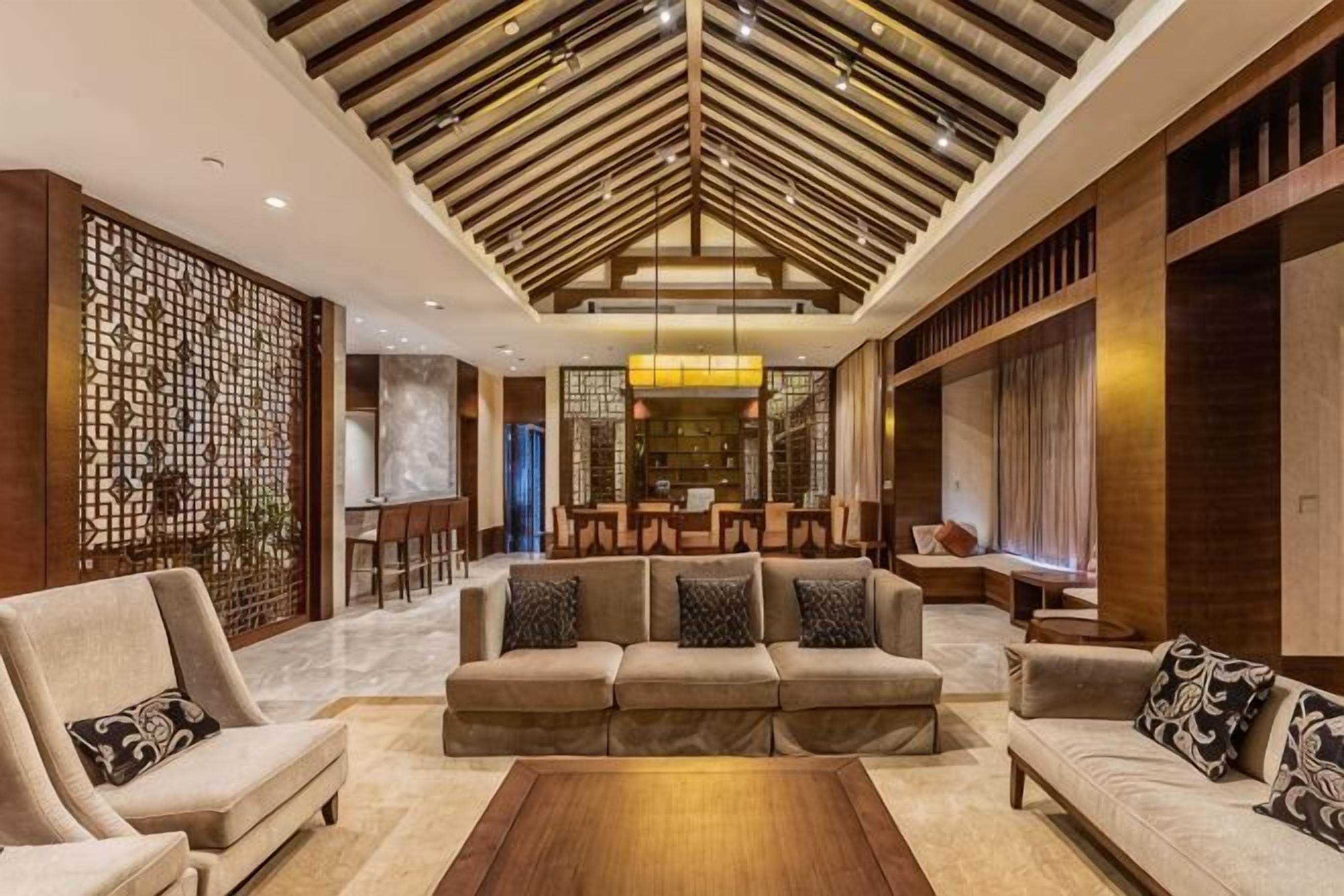 Amplia sala de estar con techo alto, un conjunto de sofás, una mesa de centro y un comedor al fondo.