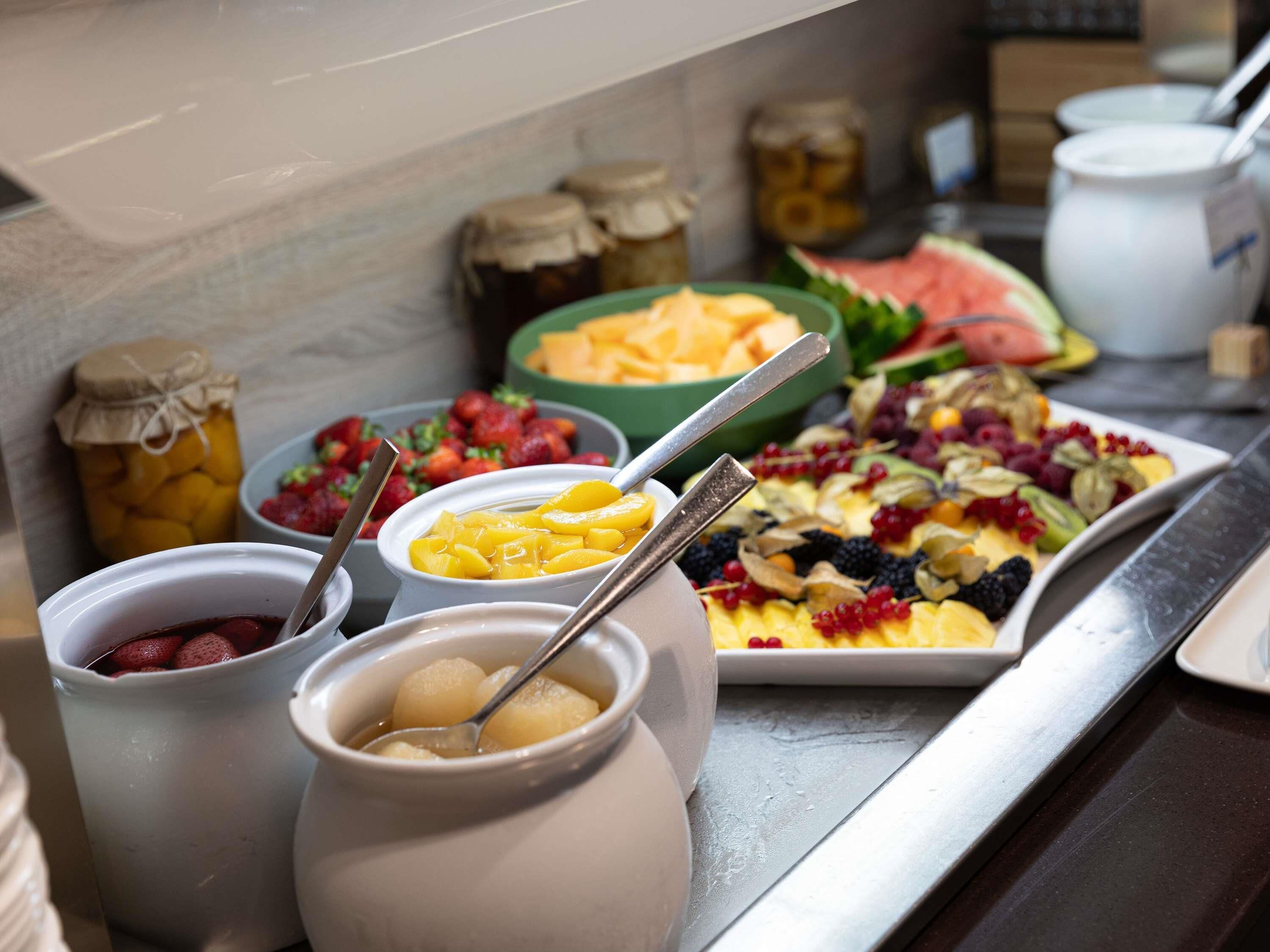 A buffet with various fruits and desserts.