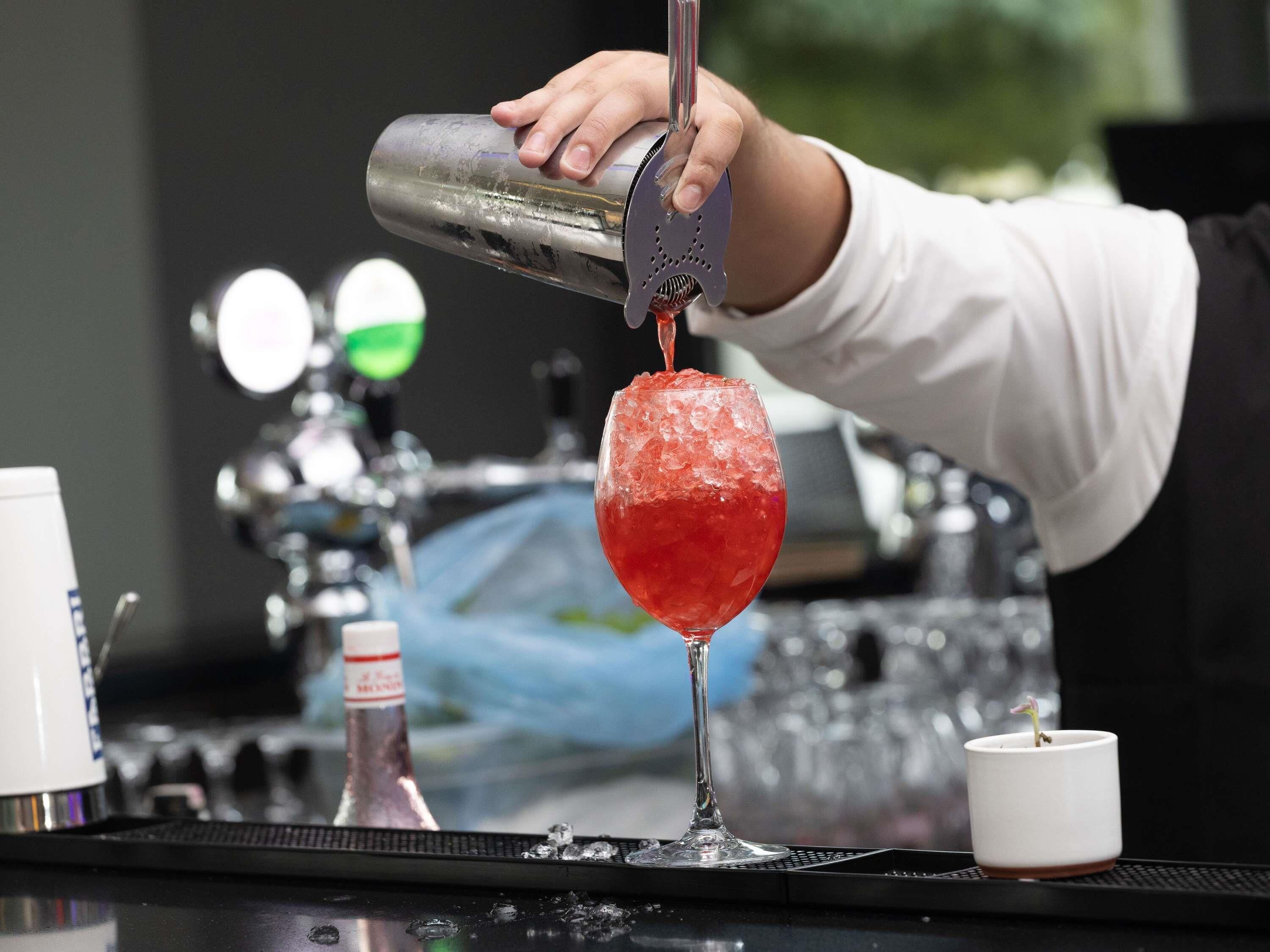 A bartender pouring a drink into a glass.