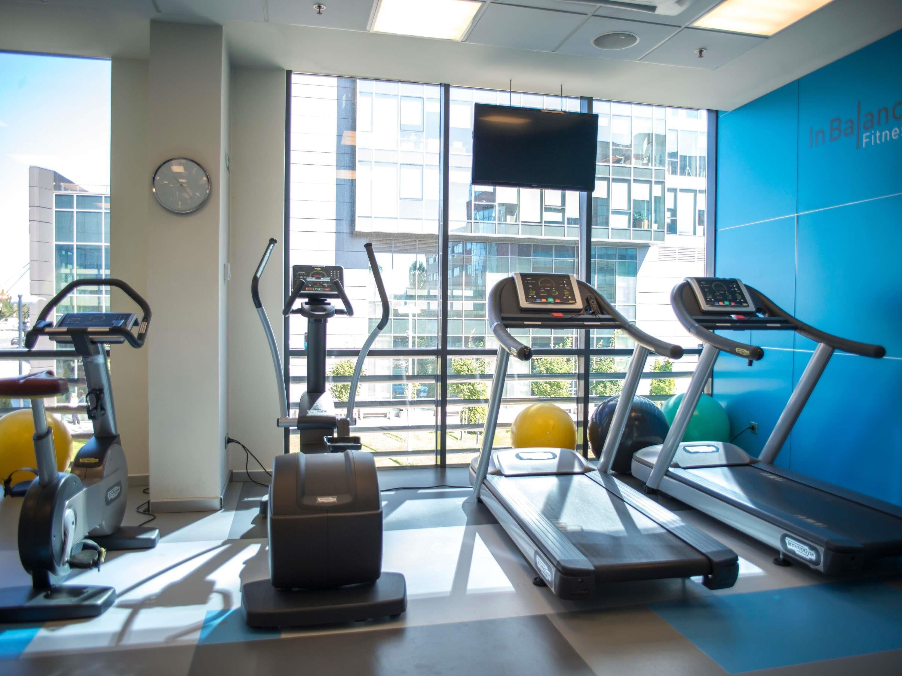 Un gimnasio con cintas de correr, elípticas y pelotas de ejercicio.
