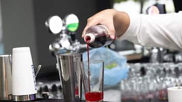 A bartender pouring a red liquid into a glass.