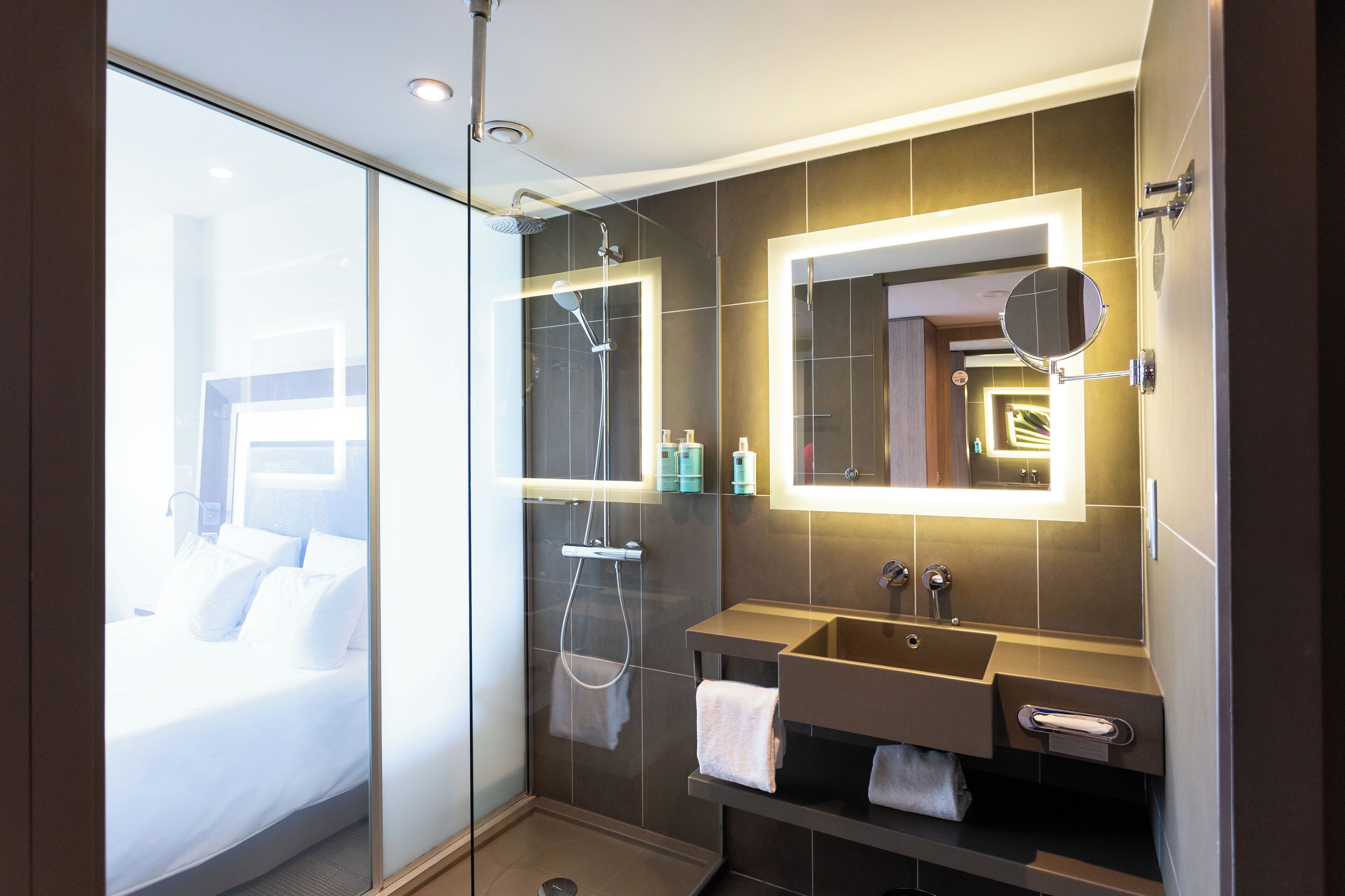A modern bathroom with a glass shower enclosure, a large mirror, and a built-in sink.