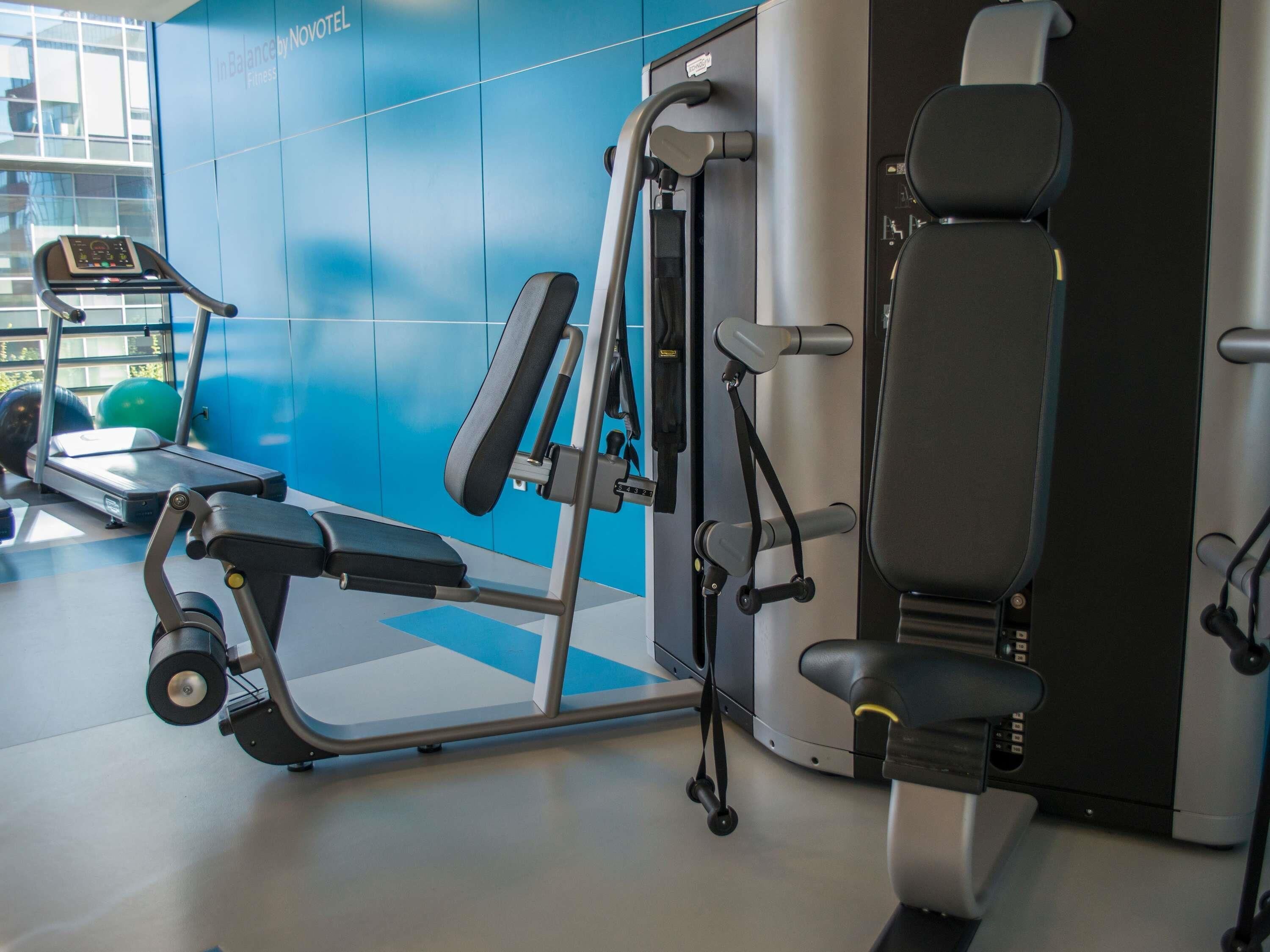 Un gimnasio con equipo de ejercicio, una cinta de correr y una pared con un diseño azul.
