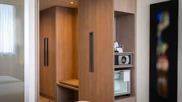 A hotel room with a bed, a seating area, a microwave, and a refrigerator.