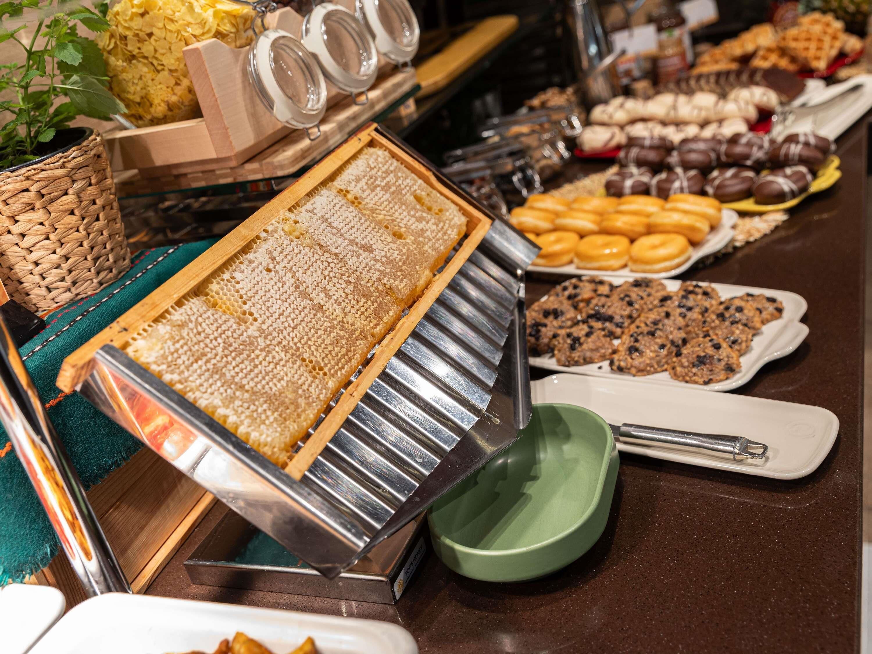 Un buffet proposant une variété de plats, notamment du miel en rayon, des pâtisseries et des biscuits.