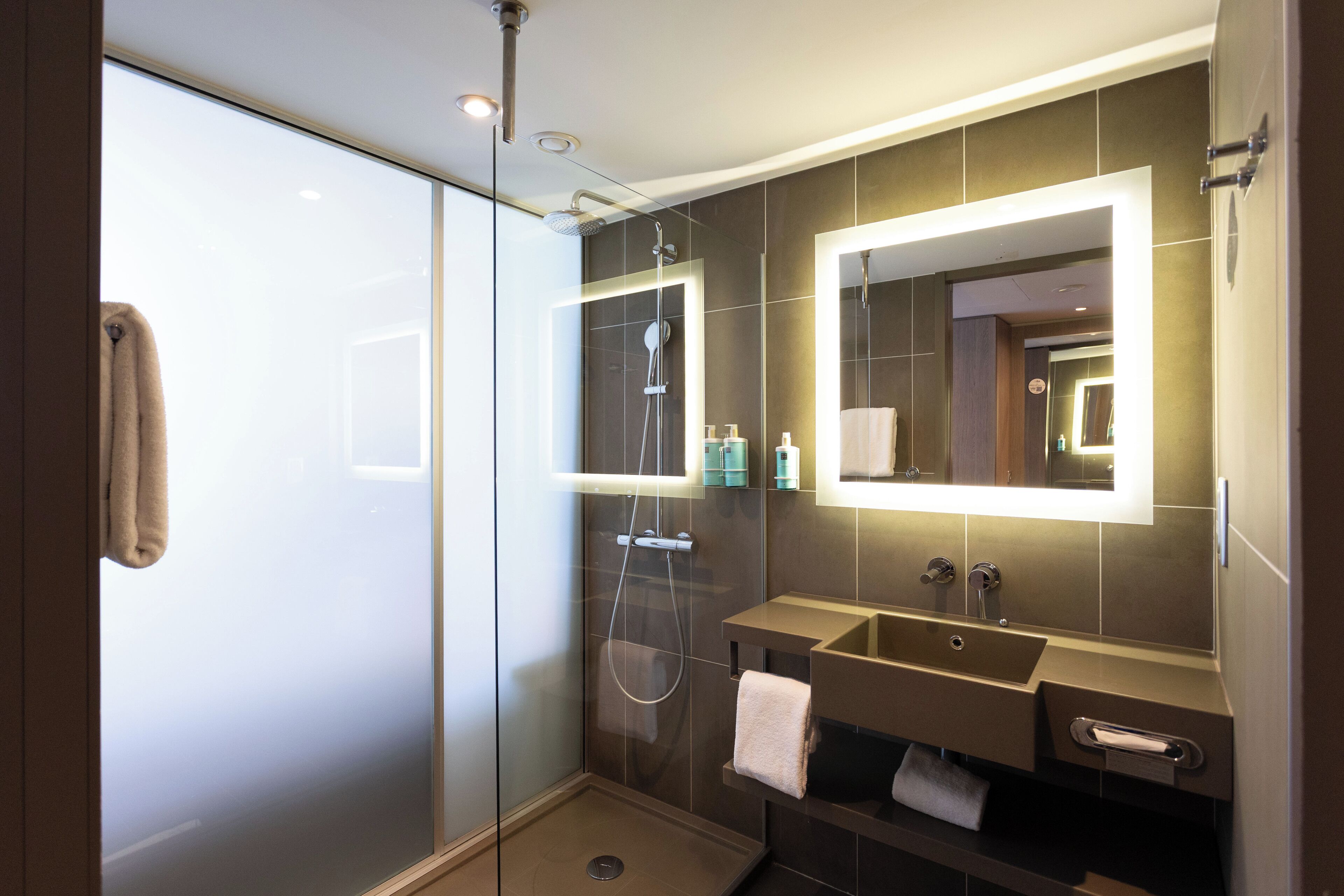 Un bagno moderno con cabina doccia in vetro, un mobile vanità con specchio e un porta asciugamani.