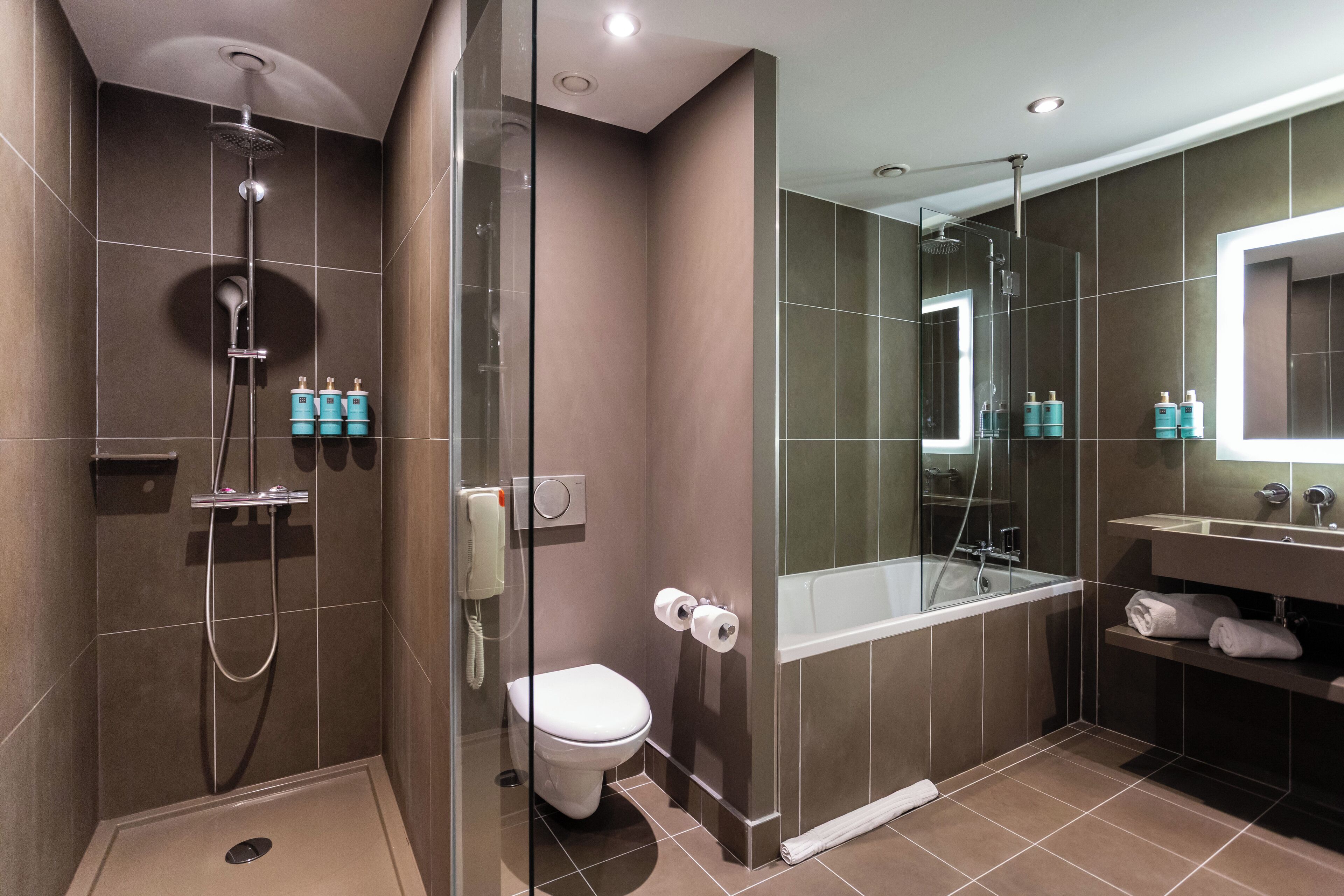 A modern bathroom with a glass-enclosed shower, a toilet, a bathtub, and a vanity with a mirror.