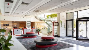 A modern hotel lobby with a reception desk, seating areas, and a staircase. - Novotel Sofia (Sofia)