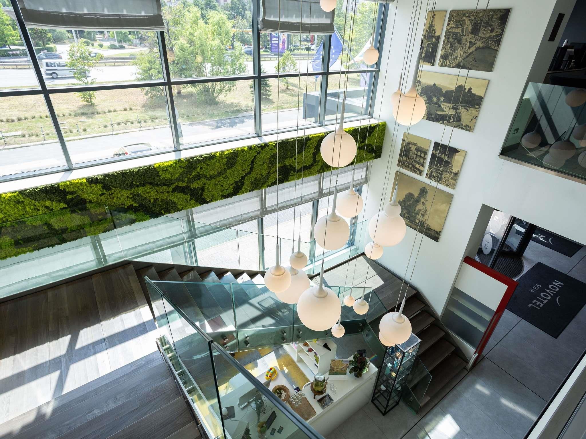 A modern interior with a glass staircase, hanging pendant lights, and a green wall.