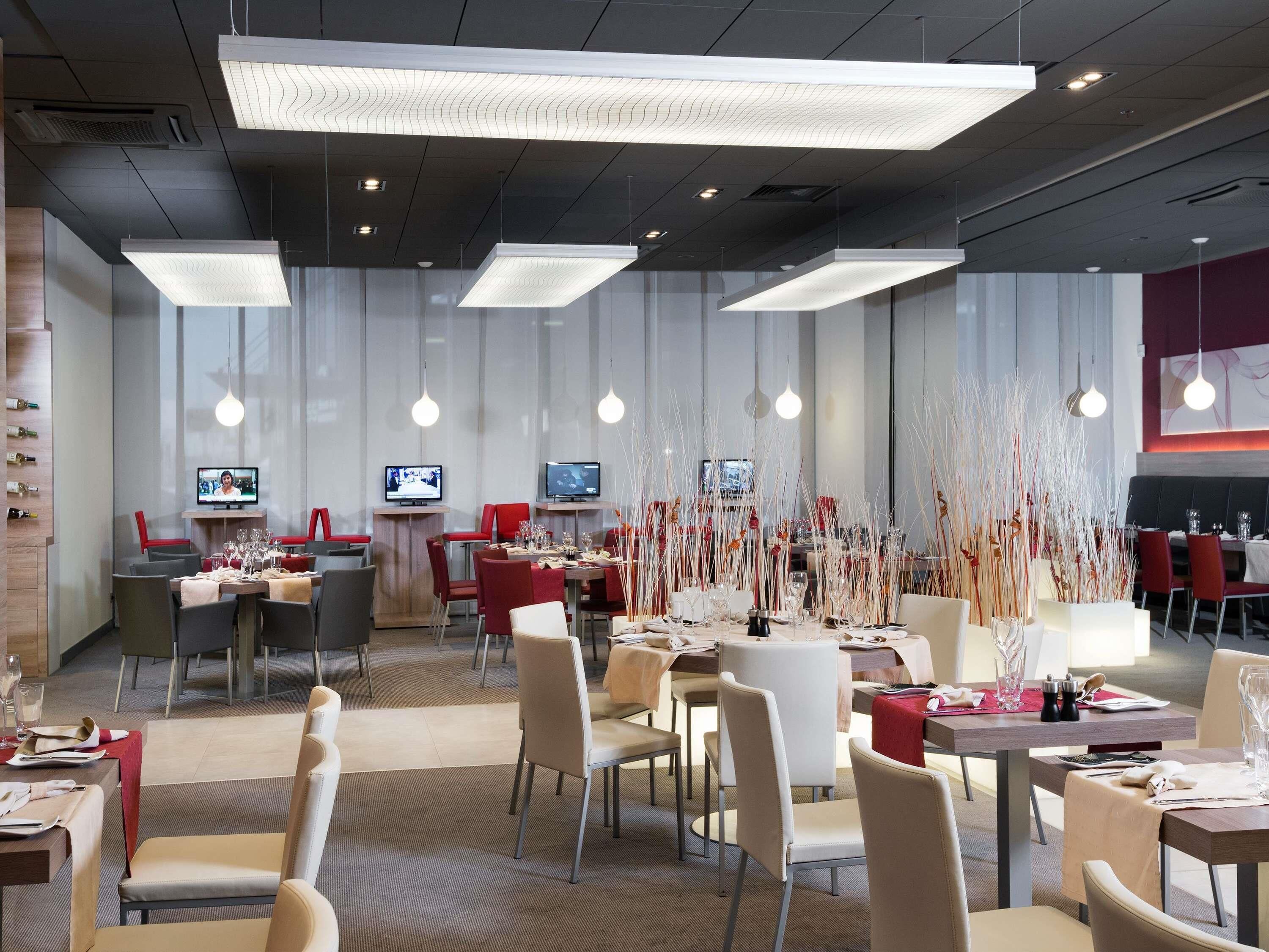 Un restaurante moderno con varias zonas de comedor, televisores de pantalla plana y decoración contemporánea.