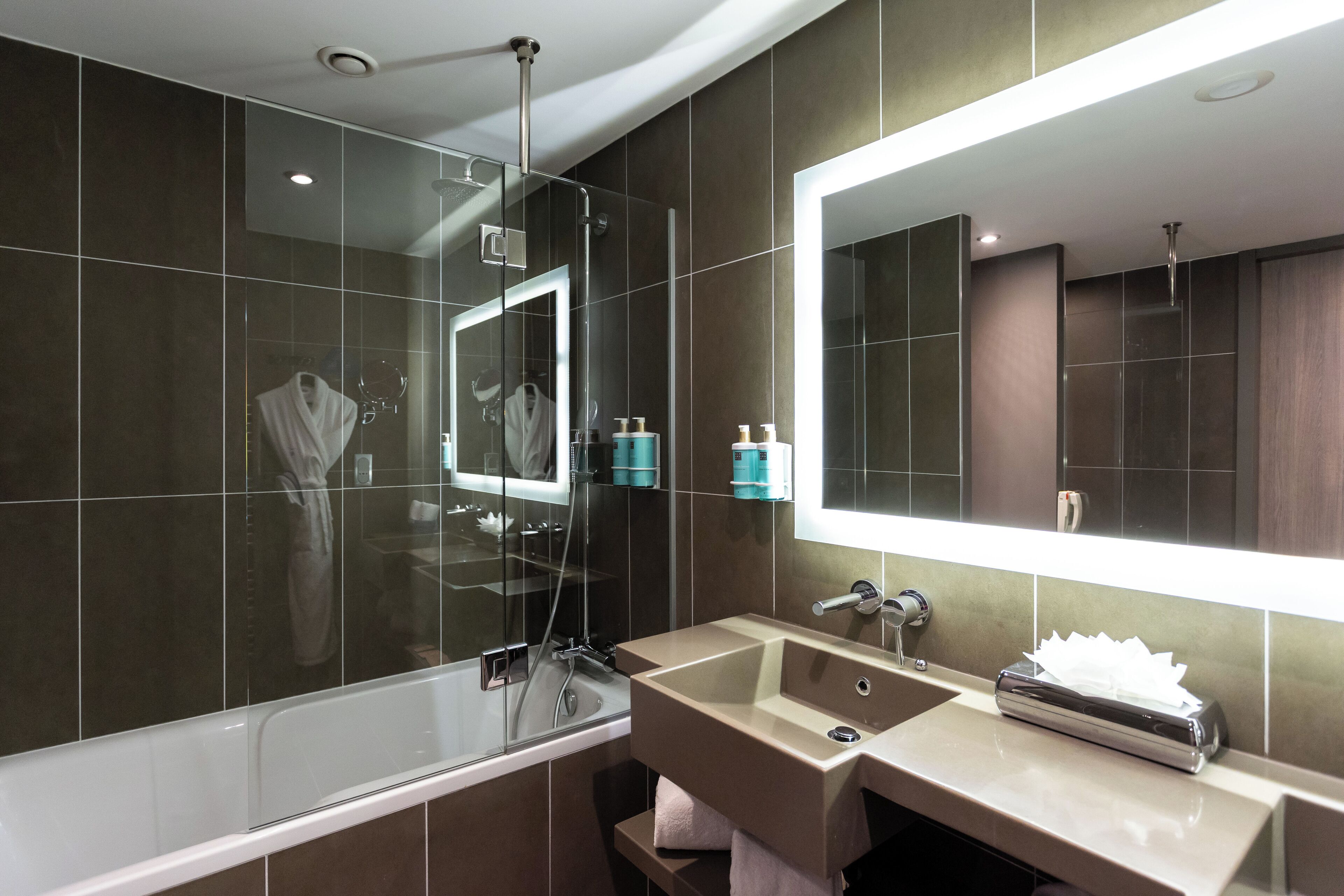 Une salle de bain moderne avec une baignoire, un lavabo et un grand miroir.