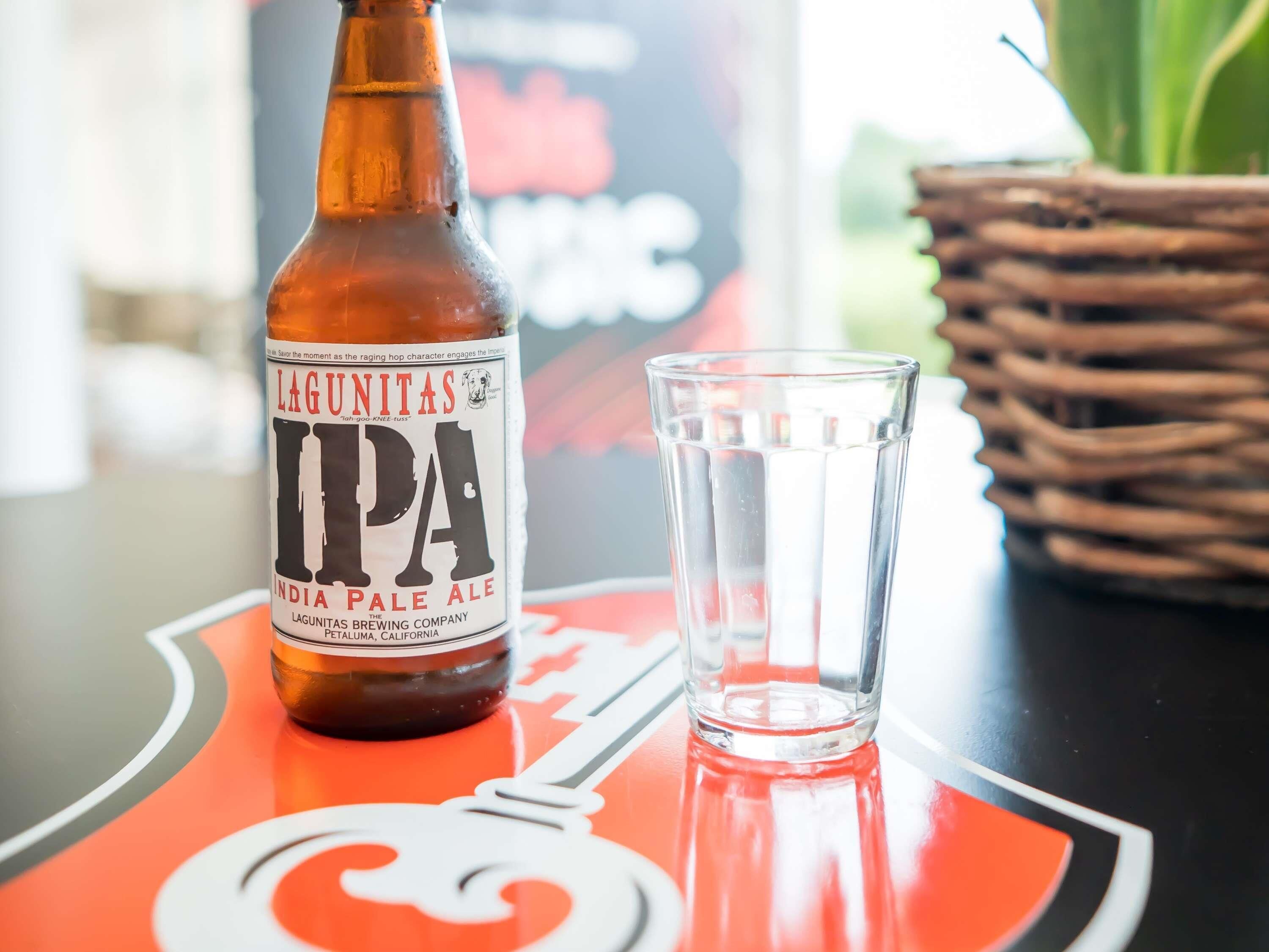 Una botella de IPA Lagunitas y un vaso sobre una mesa con un logotipo.