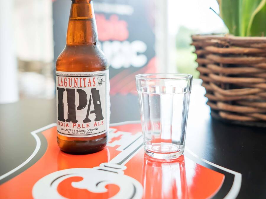 Una botella de IPA Lagunitas y un vaso sobre una mesa con un logotipo.