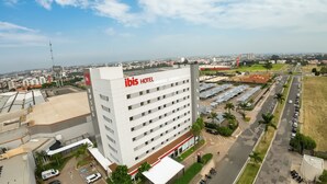 Un hôtel moderne, reconnaissable à son grand panneau « IBIS HOTEL », entouré d’un parking et offrant une vue sur le paysage urbain.