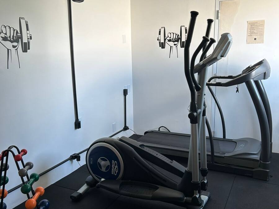 Un gimnasio en casa con una bicicleta estática, una elíptica y un banco de pesas.