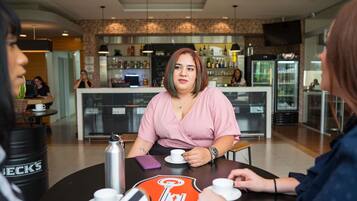 Una cafetería con mostrador, mesas y dispensador de bebidas.