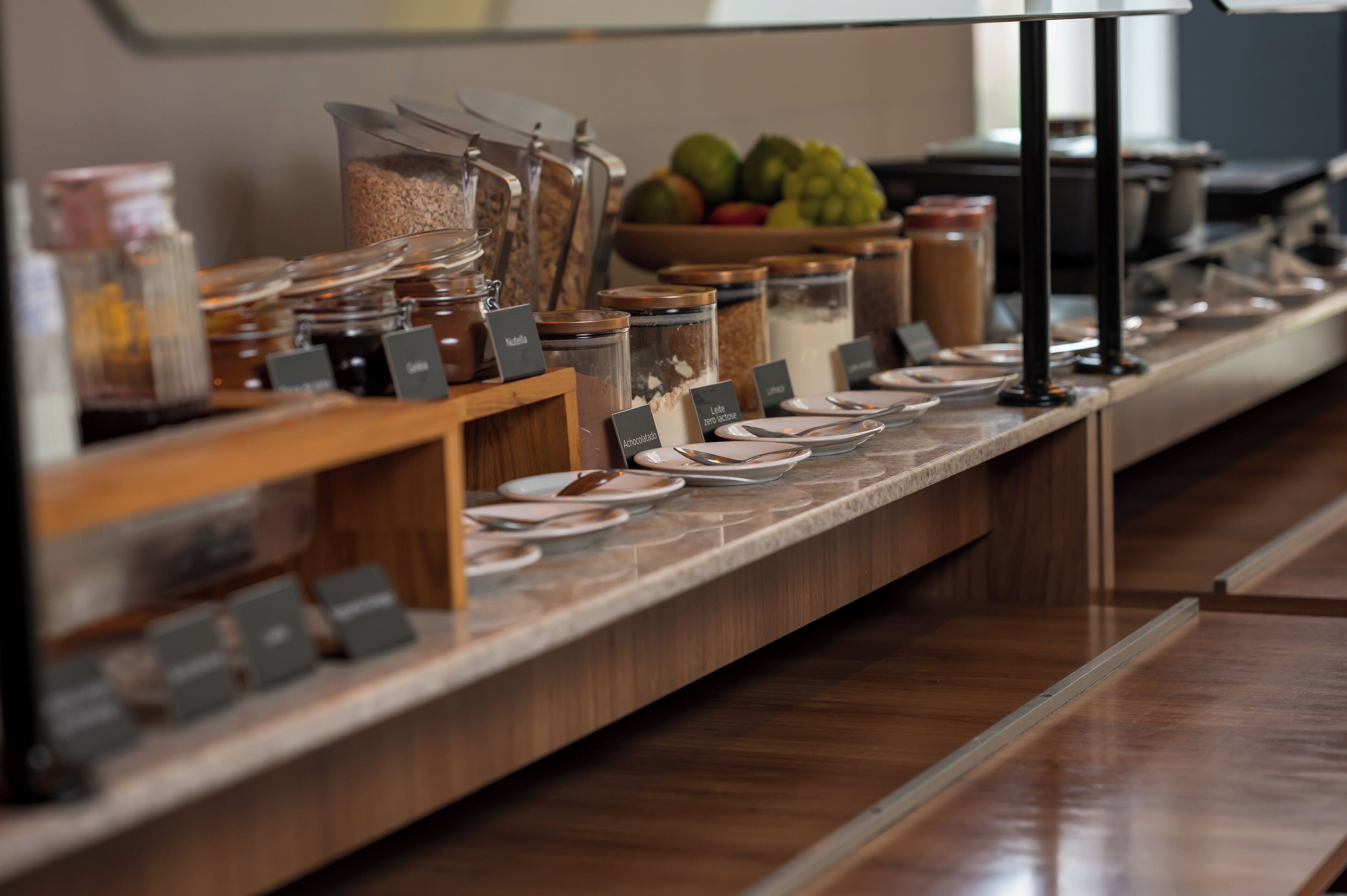 Montaje de buffet con diferentes alimentos y condimentos en recipientes de vidrio, identificados con sus nombres.