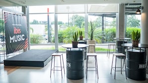 Un vaste espace intérieur comprenant une scène, des sièges et de grandes fenêtres donnant sur l’extérieur.