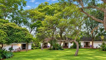 Una propiedad de estilo bungalow con un césped cuidado, varios árboles y cielo despejado.