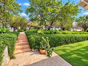 A well-maintained garden with a paved pathway leading to a house. - Musketeers Lodge (Bulawayo)