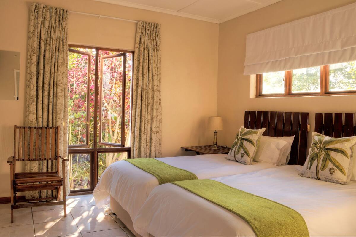 Une chambre d’hôtel avec un grand lit, deux tables de chevet, une chaise et une fenêtre avec des rideaux.