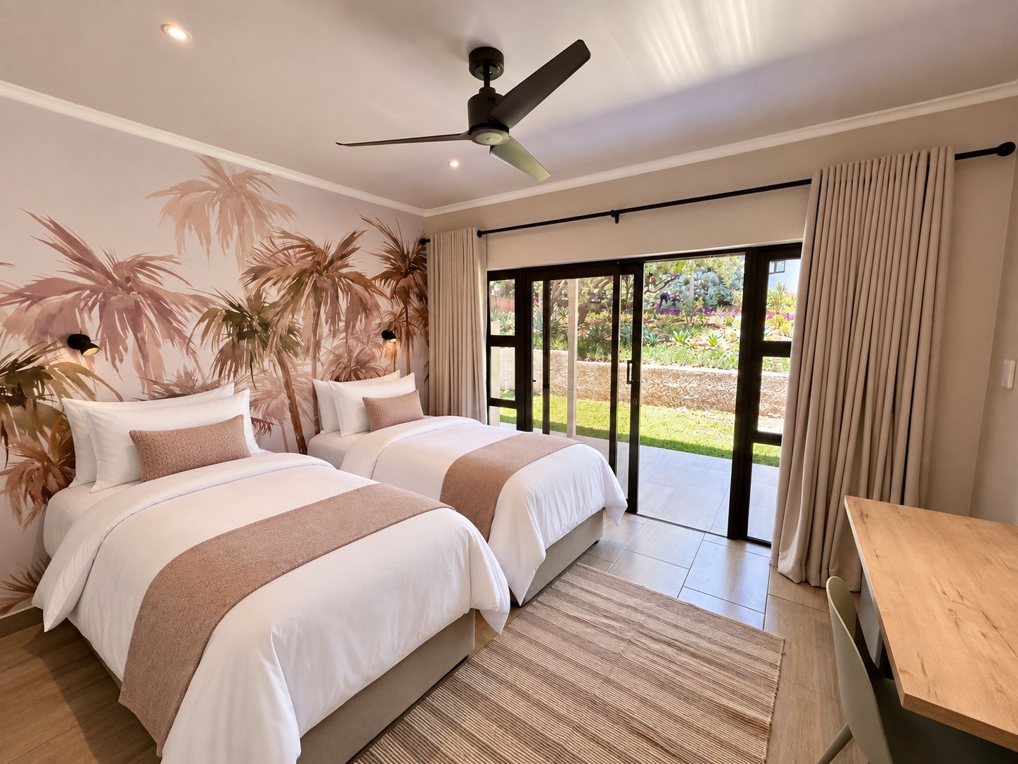 A bedroom with two beds, a ceiling fan, and a view of a garden through a sliding door.