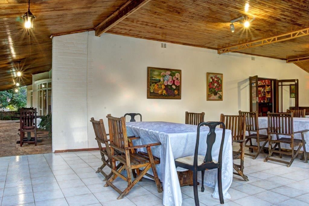 A dining area with wooden tables and chairs, white walls, and ceiling beams.