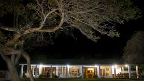 A two-story house with a covered patio area, large windows, and a well-maintained lawn. - Musketeers Lodge (Bulawayo)
