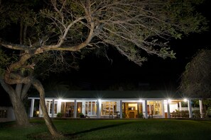 Stunning two-story building with multiple rooms and suites, set amidst a beautifully manicured lawn and a large tree.