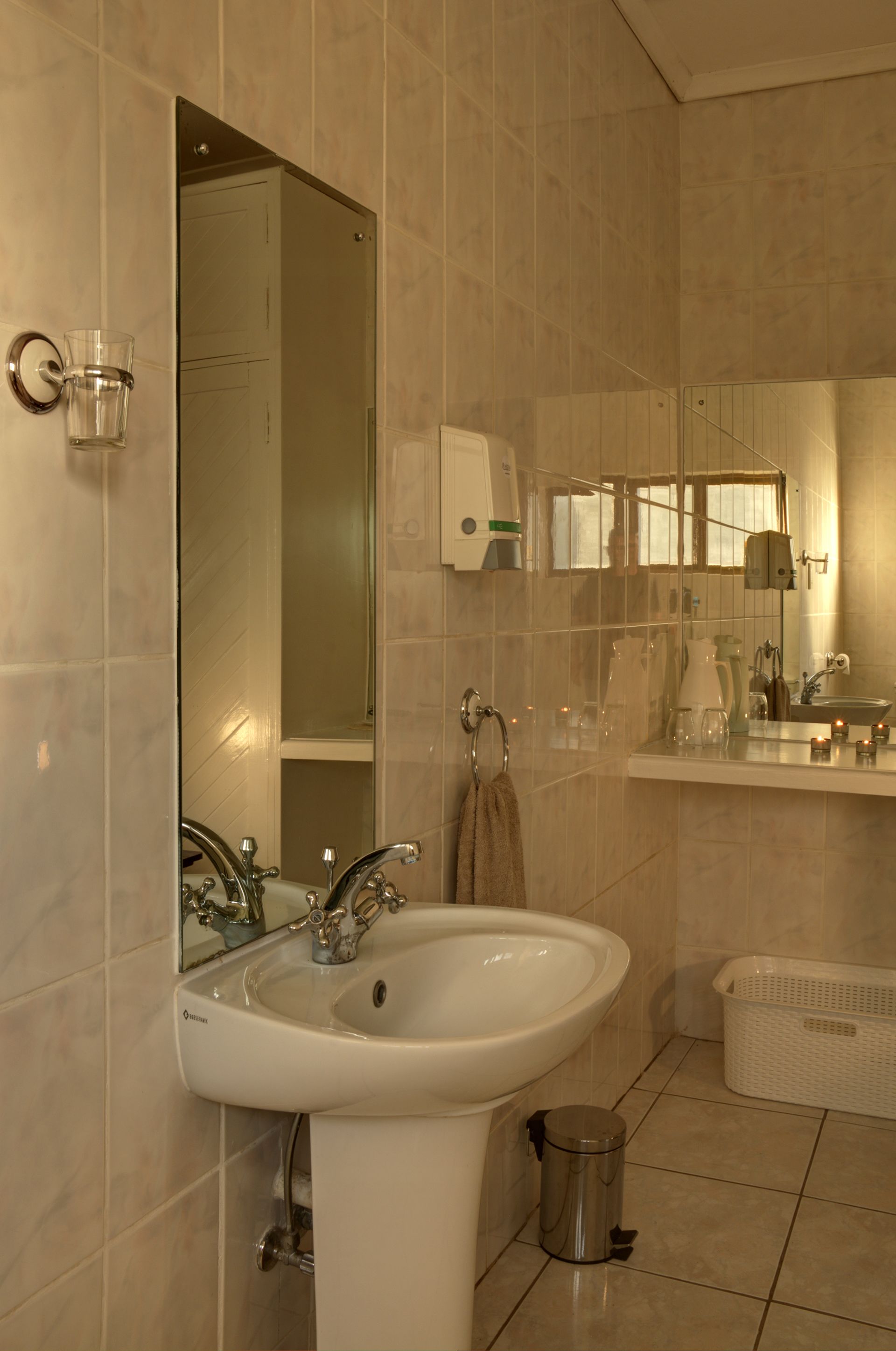 A bathroom with a white sink, mirror, and tiled walls.