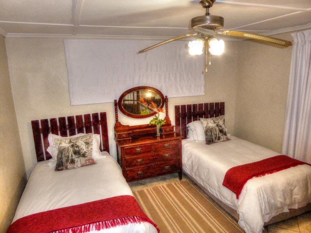 Un dormitorio con dos camas individuales, un aparador de madera, un espejo y un ventilador de techo.