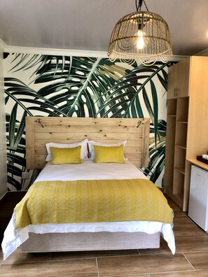Una cama con cabecera de madera, colcha amarilla y dos almohadas amarillas.
