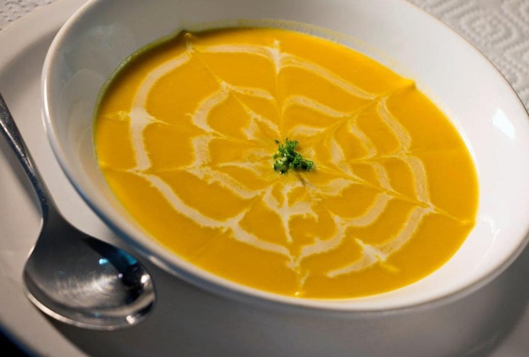 A bowl of soup with a decorative swirl pattern on the surface.