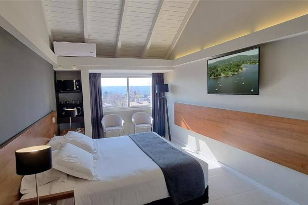 Ett modernt hotellrum med en säng, en TV, ett skrivbord med en stol och utsikt över omgivningarna.