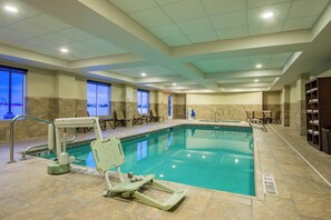 An indoor swimming pool with a diving board, chairs, and a changing room area. - Holiday Inn Express Hotel & Suites Hobbs by IHG (Hobbs)