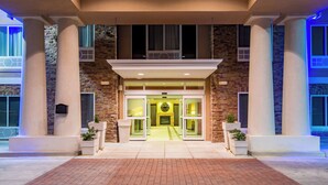 A hotel entrance with a brick facade, large columns, and a central doorway.